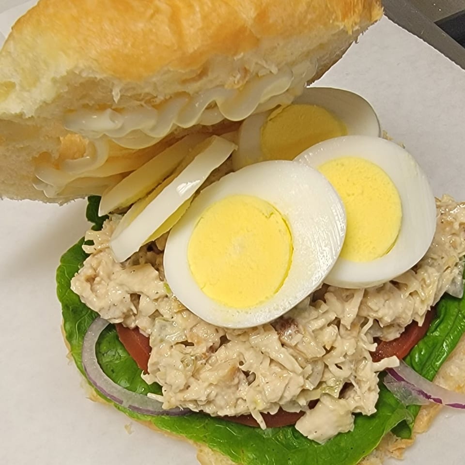 A healthy TATERSALADZ chicken salad sandwich with lettuce, tomato, onion, and hard-boiled eggs.