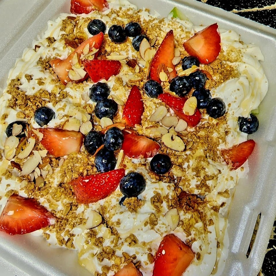 A healthy Tatersaladz fruit and yogurt bowl with strawberries, blueberries, granola, and almonds.